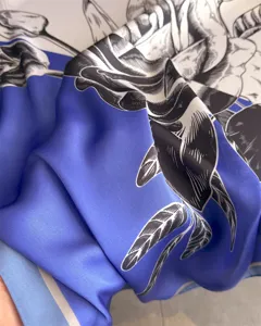 Close-up detail of luxury blue silk square scarf with elegant floral botanical print.