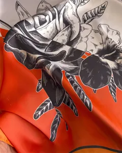 Close-up detail shot of a stylish contrast color printed silk square scarf with bold rose pattern.