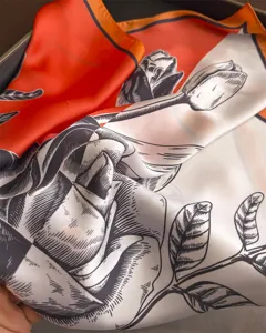 Detail view of a luxury orange and white contrasting silk scarf with elegant floral sketch print.