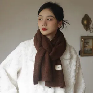 Cozy brown knitted scarf detail shot featuring a soft textured fabric and a cute mini label.