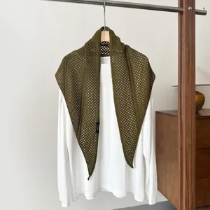 Close-up detail of the olive green crochet knit triangular shawl hanging on white tee.