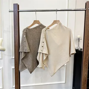 Detailed view of stylish knitted cape with metal buttons, perfect warm winter clothing accessory.