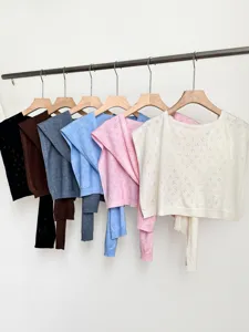 Detailed view of hollow knit shawl cardigans in multiple colors hanging neatly on wooden racks.