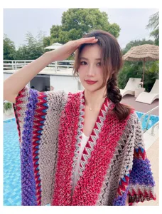 Detailed view of a colorful knitted ethnic poncho cape worn outdoors near a resort pool.