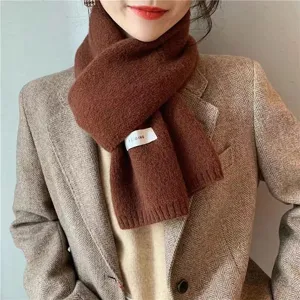 Close-up detail of the cozy brown knitted winter scarf showing soft texture and a stylish label.