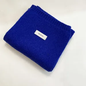 Close-up detail of the folded royal blue knitted scarf featuring a white brand label.
