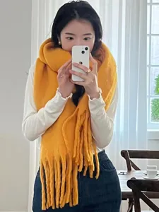 Close-up details of the thick yellow knitted winter tassel scarf, very cozy and warm.