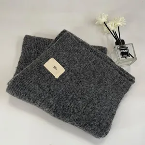 Dark grey thick knitted scarf detail showcasing soft fuzzy texture and cute woven label.