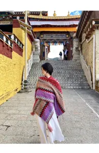 Details of the colorful ethnic knitted shawl, featuring geometric patterns and fringe hems.