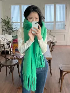 Green mohair winter scarf with cozy knit texture and fringe. Soft warm fashion accessory.