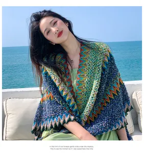 Detailed view of the colorful knitted ethnic shawl worn by model against sea backdrop.