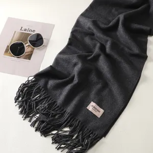 Dettaglio di sciarpa invernale spessa grigio scuro, morbida trama e frange eleganti.
