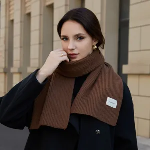 Close-up view of the cozy brown knit scarf showing its soft ribbed texture and brand detail.