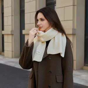Detail close-up shot of cozy ribbed knit neck warmer scarf in cream white worn outdoors.