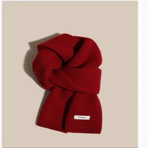 Red knitted wool scarf close-up detail, showing soft texture and cozy winter accessory style.