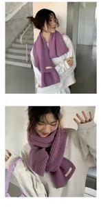 Knitted winter scarf in solid purple with woven label detail, soft and warm fashion accessory.