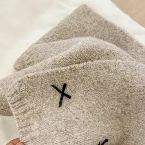 Knit scarf detail showcasing soft beige woolen fabric texture and chic black bow accent.