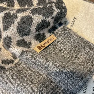 Primo piano della trama della sciarpa in maglia leopardata con etichetta in pelle invernale