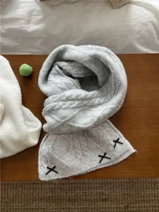 Close-up detail of a grey cable-knit winter scarf featuring cute black ribbon accents.