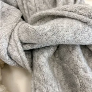 Detail view of the soft grey knit winter scarf, showing warm cable texture and cozy fabric.