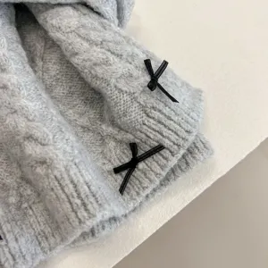 Close-up detail of winter knit scarf with cute black bow decorations, soft texture.