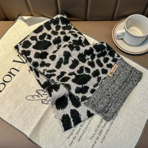 Primo piano sui dettagli di una sciarpa a maglia con stampa leopardata e tazza di caffè.