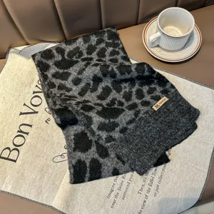 Vista dettagliata di una sciarpa in maglia con stampa leopardata nera e grigia su un tappetino.