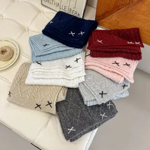 Close-up detail shot of cute knitted winter scarves in multiple colors with bow embroidery.