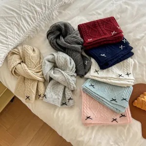Detailed view of winter knitted woolen scarves with cute bow embroidery in various solid colors.