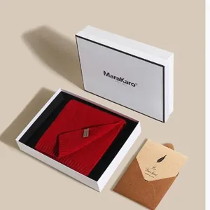 Red knitted wool scarf in elegant white gift box with greeting card for winter warmth