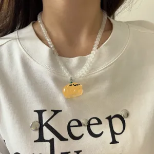 Primer plano de un collar de cuentas con colgante calabaza fantasma de Halloween, joya.