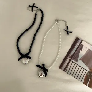 Detailed view of sweet heart bow pearl necklaces in black and white styles, elegant clavicle chain.
