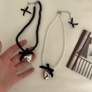 Chic pearl bead choker necklace with a silver heart pendant and black bow. Stylish women jewelry.