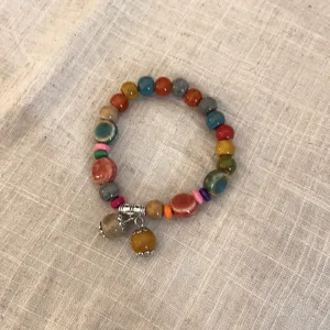 Primer plano detallado de la pulsera de cuentas étnicas con dijes de cerámica y madera.
