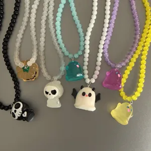 Primer plano detallado de collares de cuentas con colgantes de fantasma y calabaza de Halloween.