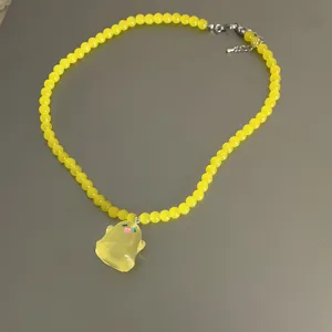 Collar de cuentas amarillas con bonito colgante de fantasma translúcido, primer plano detallado de moda.
