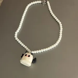 Primer plano detalle del collar de cuentas blancas con colgante de fantasmita lindo.