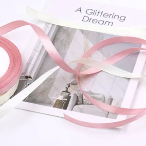 Close-up detail of smooth satin ribbons in pink and cream, perfect for gift wrapping and decor.
