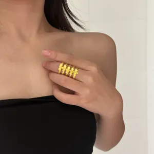 Large bague statement dorée élégante avec un design ajouré complexe à bandes multiples.