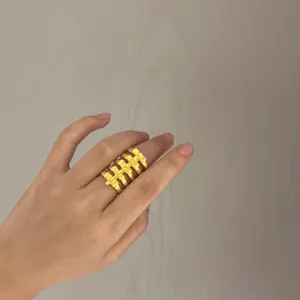 Bague large dorée tendance avec un design d'os creux unique pour femme, bijou de mode chic.
