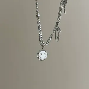 Silver multi-layered rhinestone necklace with coin and safety pin charms, trendy punk style.