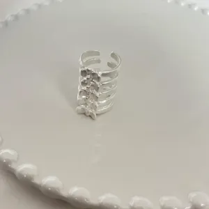 Gros plan d'une bague ouverte en metal argente avec une forme unique de vertebre.