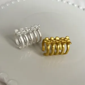 Gros plan détaillé de bagues larges argentées et dorées, au design avant-gardiste unique.