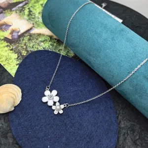 Close-up of the delicate dual flower pendant necklace with white enamel and sparkling zircon.