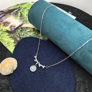 Close up view of silver zircon curved pendant necklace on blue velvet display prop detail.