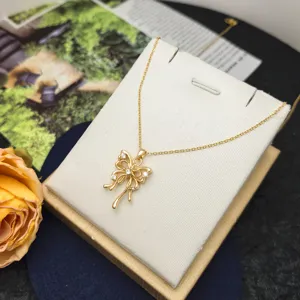 Vue détaillée de l'élégant collier nœud plaqué or avec des zircons scintillants sur support.