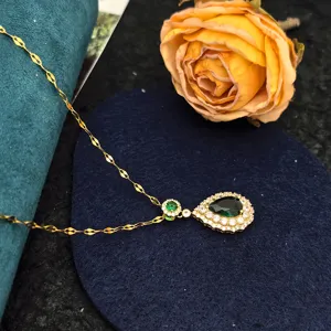 Close-up view of emerald pear pendant necklace with delicate gold chain and sparkling zircon.