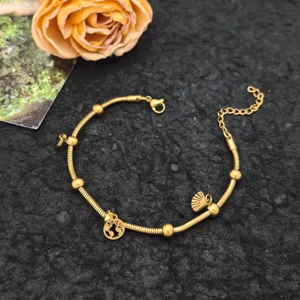 Gold snake chain bracelet with globe and shell pendants, detailed close-up view shot.
