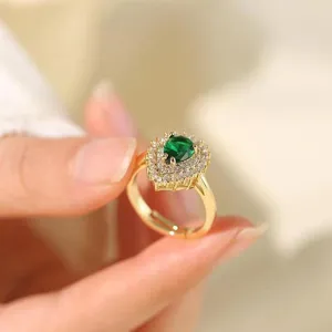 Close-up detail of luxurious gold ring featuring pear green stone and sparkling cubic zirconia halo.
