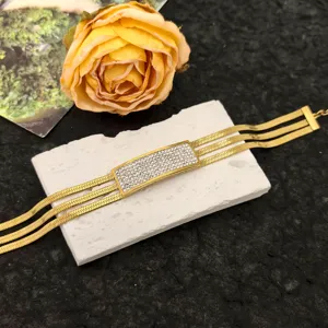 Detailed close-up of a multi-strand gold snake chain bracelet with sparkling rhinestone rectangle.